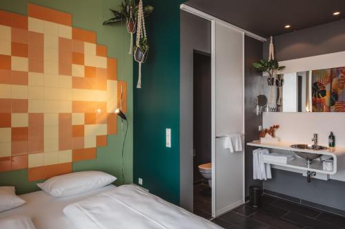 a room with a bed and a bathroom with a sink at Superbude Hamburg Altona in Hamburg