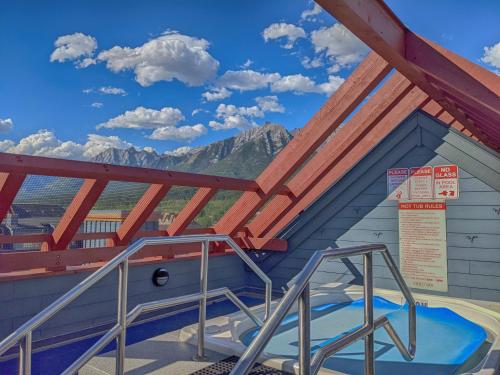 a building with a roof with mountains in the background at Pinnacle Mountain View Condo 3 Bed 2 Bath Downtown Canmore in Canmore