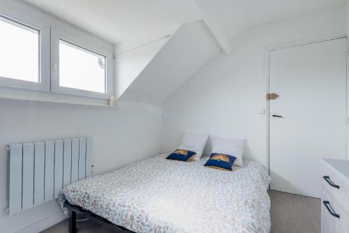 a white bedroom with a bed and two windows at Appartement à 300m de la plage - Extérieur commun in Asnelles