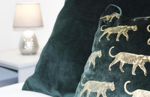 a green pillow with lions on it next to a lamp at Didcot - Private Flat with Garden & Parking 08 in Didcot