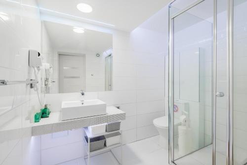 biała łazienka z umywalką i prysznicem w obiekcie Accent w mieście Nowy Dwór Gdański