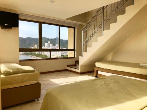 1 dormitorio con 2 camas y una escalera con ventana. en Edificio El Peñon del Rodadero, en Santa Marta
