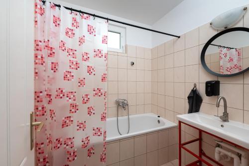 ハイドゥソボスローにあるMonika Apartmanのバスルーム(シャワーカーテン、バスタブ、シンク付)