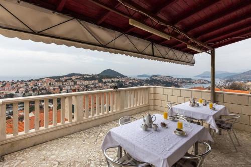 two tables on a balcony with a view of a city at Rooms Ivo in Dubrovnik