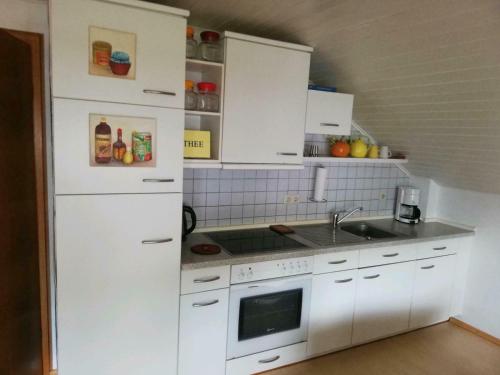 una cocina con armarios blancos y fregadero en Ferienwohnung / Monteurswohnung in ruhiger Waldlage en Borghees