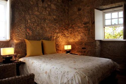 um quarto com uma cama com 2 candeeiros e 2 janelas em Casa das Saras em Gonçalo