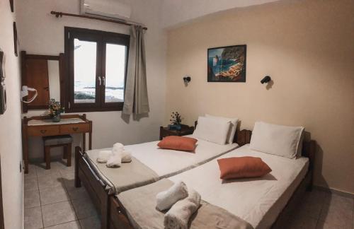 a bedroom with two beds and a desk and a window at Anthoula Apartments in Kokkini Khanion