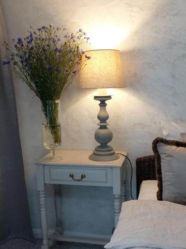 a table with a lamp and a vase of flowers on it at Naktakės apartamentai in Kupiškis