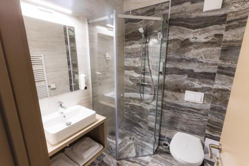 a bathroom with a sink and a shower at Nedei Hotel&Spa Transalpina in Martinie