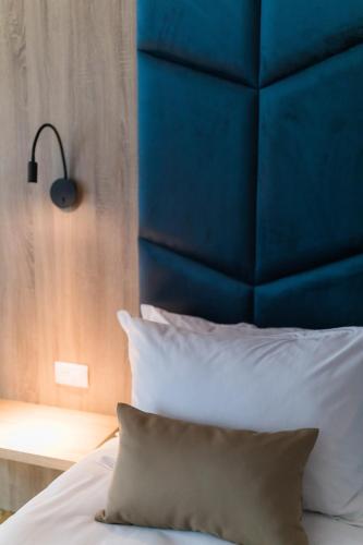 a bed with a blue headboard and a pillow at Nedei Hotel&Spa Transalpina in Martinie