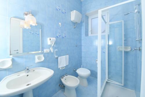 Baño azul con lavabo y aseo en Albergo Atlantic, en Isquia