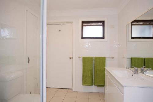 Baño blanco con lavabo y aseo en Geelong Holiday Home, en Geelong