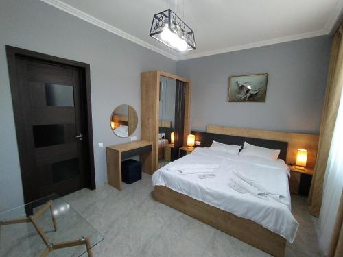a bedroom with a large white bed and a mirror at Nice Apartments Tbilisi in Tbilisi City