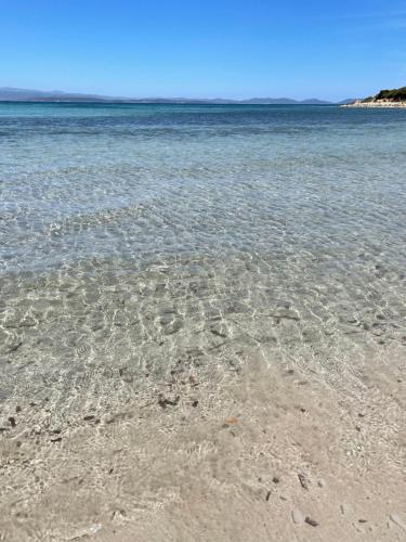 a beach with crystal clear water on a clear day at Casa Kant in SantʼAntìoco