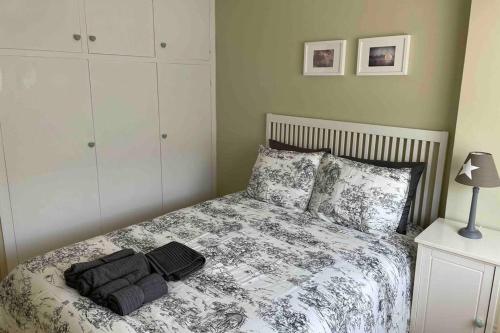 1 dormitorio con 1 cama con edredón blanco y negro en Coqueto apartamento cerca de la playa, en Santander