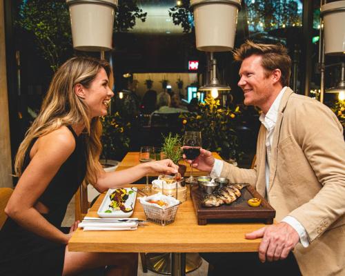 a man and woman sitting at a table with a plate of food at SLS Brickell in Miami