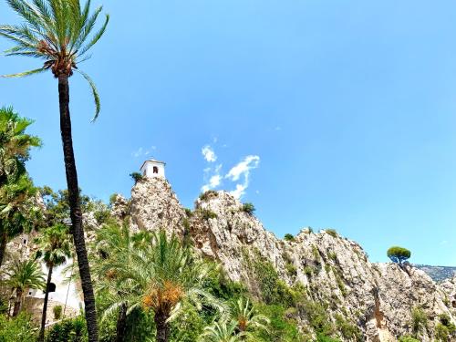 a mountain with palm trees and a lighthouse at Ideal Apartamento - Guadalest in Guadalest