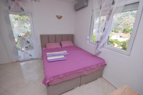 a small bedroom with a purple bed with two windows at Subotic S apartmani in Risan