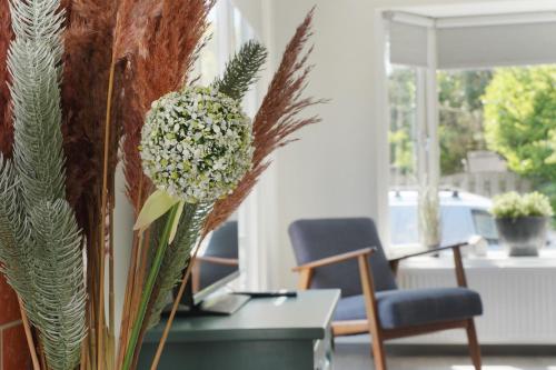 a vase of flowers on a table in a living room at Gezellig en relaxed verblijf in chalet in Putten op de Veluwe! in Putten