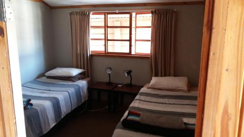 um pequeno quarto com 2 camas e uma janela em The Cottage Polokwane em Polokwane