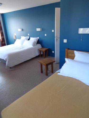 1 dormitorio con 2 camas y pared azul en Auberge des genêts d'or, en Ranchal