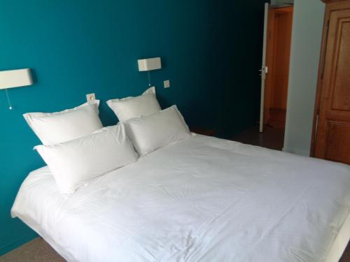 a white bed with white pillows and a blue wall at Auberge des genêts d'or in Ranchal