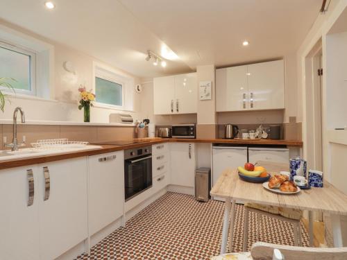 a kitchen with white cabinets and a table with a bowl of fruit at Lower Deck in Bexhill