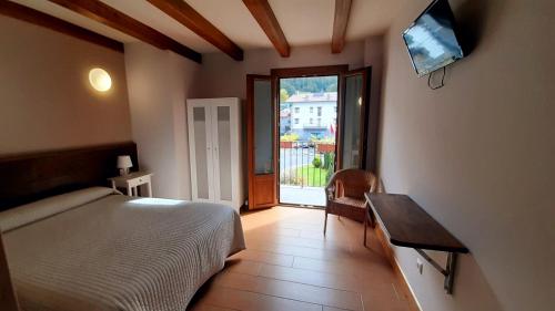een slaapkamer met een bed, een tafel en een raam bij Hostal Lopenea in Leitza