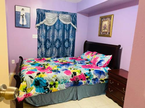 a bed with a colorful comforter and a window at 2 Bedroom Cozy Home Near EWR/NYC in Newark