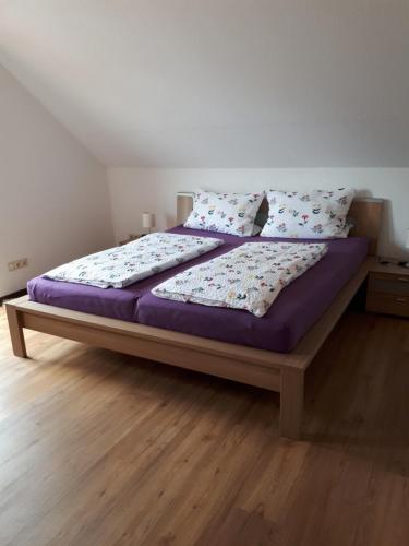 Una cama con sábanas y almohadas moradas en un dormitorio. en Haus Rosi, en Weiskirchen