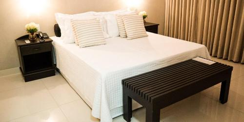 a bedroom with a large white bed and a table at Vila Romana Park Hotel in Três Lagoas