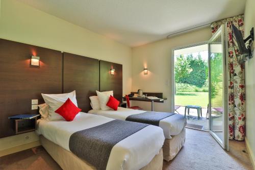 Habitación de hotel con 2 camas con almohadas rojas en The Originals Boutique, Hôtel Le Cap, Gap Sud en Tallard