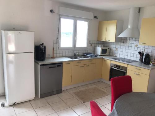 a kitchen with yellow cabinets and a white refrigerator at Maison bord de Lac de Pareloup in Salles-Curan