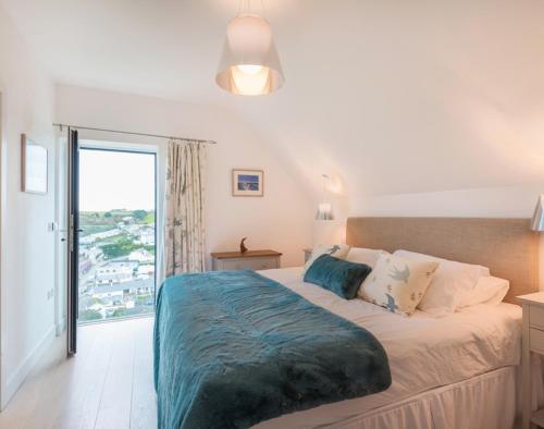 a bedroom with a large bed and a balcony at Stepper Point in Polzeath