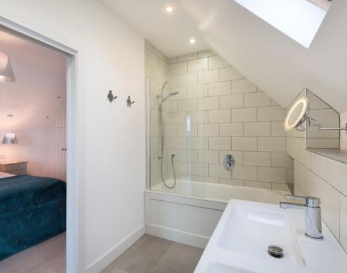 a white bathroom with a sink and a shower at Stepper Point in Polzeath