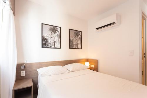a bedroom with a white bed and two pictures on the wall at Beach Class Santa Maria by Easy Home in Recife