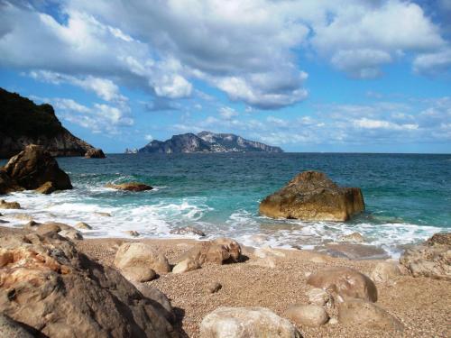 a beach with rocks and the ocean with mountains at Villa Mariel Suites & Apartment in Massa Lubrense