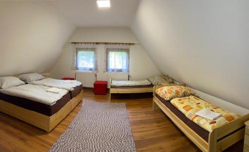 a attic room with three beds and a rug at Tavas Vendégház in Karancsalja