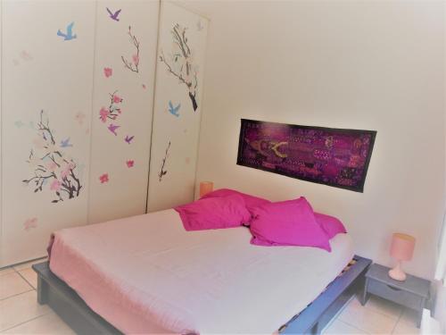 a bedroom with a bed with pink sheets and butterflies on the wall at Maison De Village in Saint-Raphaël