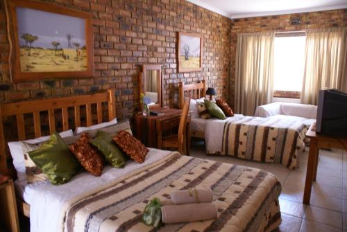 a hotel room with two beds and a tv at Emerald Guesthouse in Kempton Park