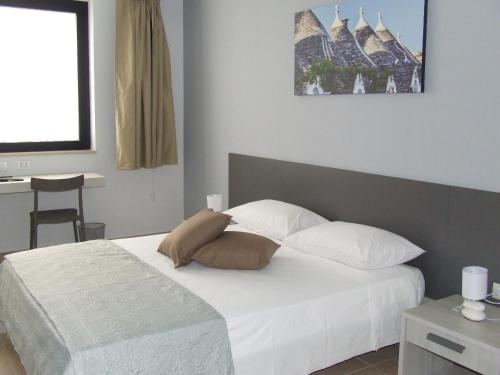 特里尼塔波利的住宿－L'incontro，一间卧室配有带白色床单和枕头的床。