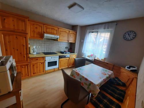 eine Küche mit Holzschränken, einem Tisch und einer Uhr in der Unterkunft Ferienhaus Waterstrat in Stolberg i. Harz