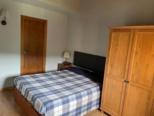 1 dormitorio con 1 cama y armario de madera en Acogedor apartamento en La Molina, en La Molina