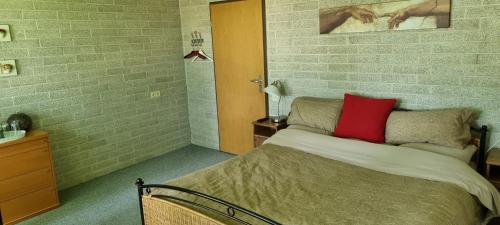 een slaapkamer met een bed met een rood kussen erop bij B&B Krachtwijk in Soest