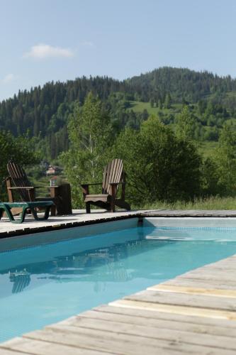 a swimming pool with two chairs and a table at Котедж з неймовірними краєвидами, Карпатський Чан DREAM, Чан Джакузі in Slavske