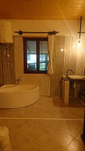 baño con bañera, lavabo y ventana en Majorka, en Balatonfenyves