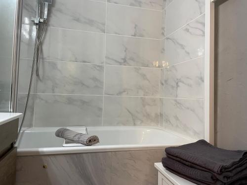 a white bathroom with a tub and a towel at T2 vue mer 6 personnes in Villers-sur-Mer