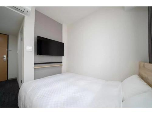 a bedroom with a white bed and a flat screen tv at R&B Hotel Nagoya Shinkansenguchi - Vacation STAY 40535v in Nagoya