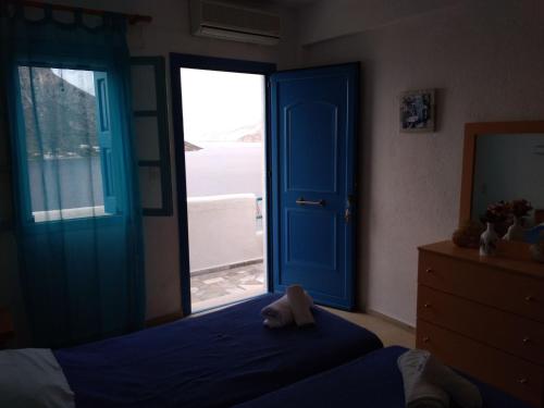 a bedroom with a blue door with a teddy bear sitting on a bed at Ariadne Studios in Kalymnos