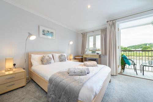 a bedroom with a large bed and a balcony at 7 Camelside in Wadebridge